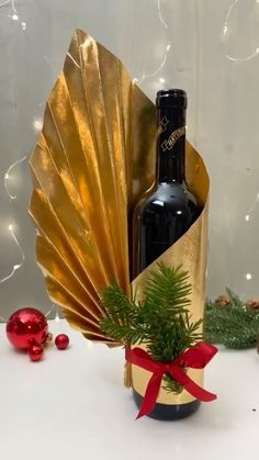 a bottle of wine sitting next to a gold fan and christmas decorations on a table