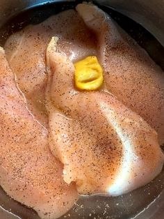 raw chicken being cooked in a pan with seasoning