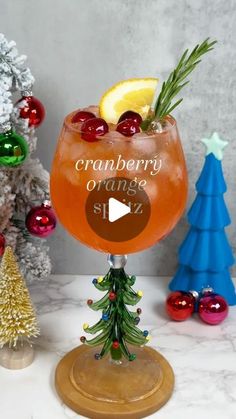 a glass filled with an orange and cranberry punch on top of a table