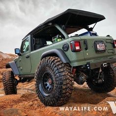 a green jeep parked on top of a rocky hill