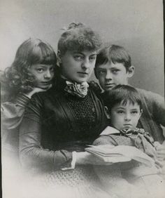 an old black and white photo of four children with one child holding the other in her arms