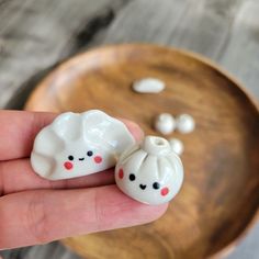 someone is holding two small white beads in their hand and they are sitting on a wooden plate