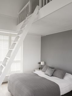 a bedroom with a bed and a white staircase leading to the second floor above it