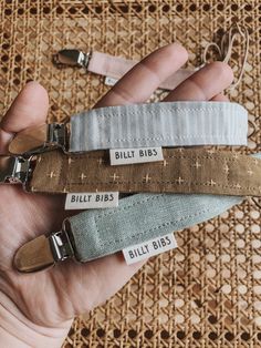 three small zippers are in the palm of someone's hand, with tags on them