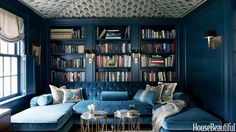 a blue couch sitting in front of a bookshelf filled with lots of books