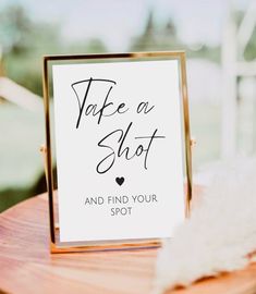 a sign that says take a shot and find your spot on a table with feathers