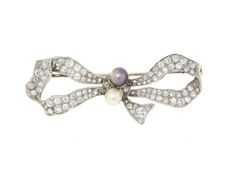 Antique Edwardian Diamond and Natural Pearl Bow Brooch in Platinum   A feminine frolic from the Edwardian era, this antique diamond and natural pearl bow brooch is a gift to be treasured. The palest platinum creates a gorgeously formed bow set with the shimmer of pave diamonds. A pair of delicate natural pearls dots the center of this sweet brooch. The Edwardian Era, 1920s Jewelry, Titanic Jewelry, Pearl Bow, Edwardian Jewelry, Bow Brooch, Jewellery Marketing, Diamond Brooch, Brooch Jewelry