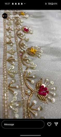 an applique on the side of a white cloth with gold and red beads