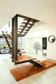 a modern staircase in the middle of a living room with white tile flooring and wooden steps