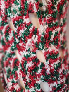 a crocheted red and green scarf hanging on a wall