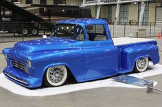 an old blue pickup truck parked in a parking lot