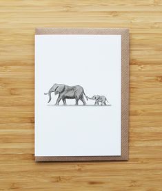 an elephant and its baby walking together on a wooden surface with a white card in the foreground