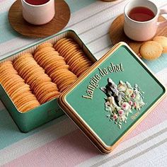 there is a box of crackers next to two cups of tea on the table