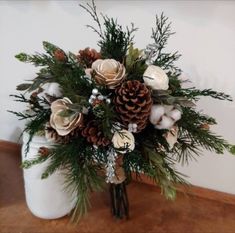 a white vase filled with flowers and pine cones