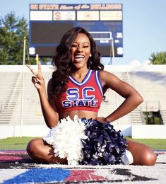 a cheerleader is sitting on the ground with her pom poms in hand