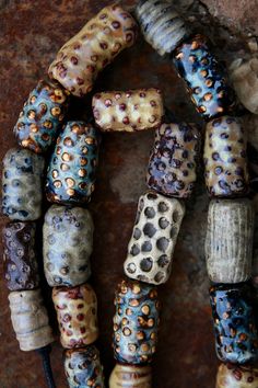 the beads are all different colors and patterns on display in front of a stone wall