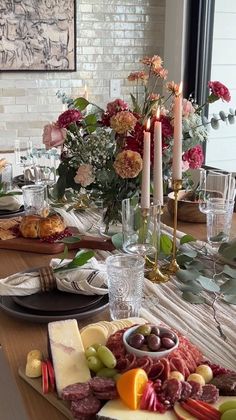 a wooden table topped with lots of plates and food next to a vase filled with flowers