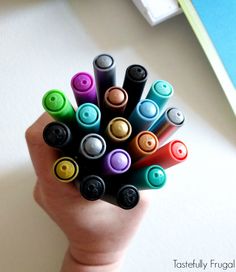 a hand holding a bunch of different colored crayons