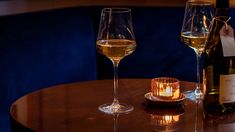 two wine glasses sitting on top of a wooden table next to a bottle of wine