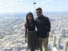 a man and woman standing on top of a tall building in front of a cityscape