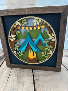 an origami cut out of paper with a campfire and trees