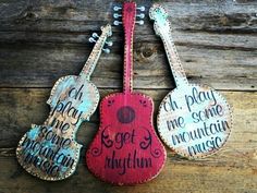 two wooden guitars with words on them hanging from the side of a wood plank wall