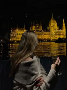 a woman sitting on a couch in front of a large building at night with the lights on