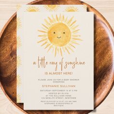 the little ray of sunshine is almost here baby shower or birthday party card on a wooden plate