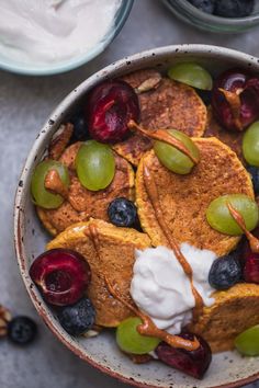 a bowl filled with pancakes and fruit next to yogurt