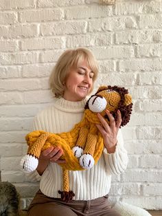 a woman sitting on the floor holding a stuffed animal in her hands and smiling at the camera