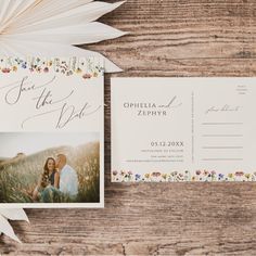 the wedding stationery is laid out on top of a wooden table with an open envelope