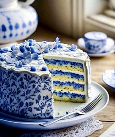 a blue and white cake sitting on top of a plate next to a tea pot