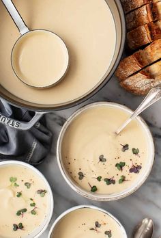 three bowls filled with soup next to some bread