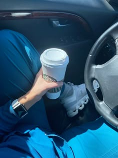 a person holding a coffee cup while sitting in a car