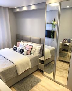 a bedroom with a large bed and mirrored closets in the corner, along with a mirror on the wall