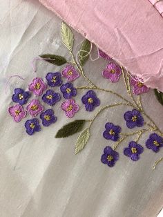 purple flowers are embroidered onto the side of a pink pillow