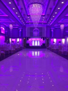 an empty ballroom with purple lighting and chandeliers