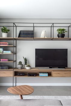 a living room with bookshelves, shelves and a flat screen tv on the wall