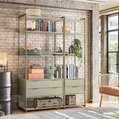 a living room filled with furniture and a book shelf next to a brick wall in front of a window