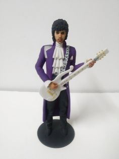 a figurine of a man with a guitar on a white background, wearing a purple outfit