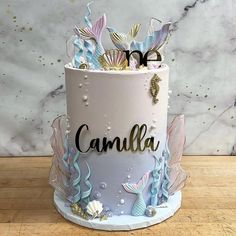 a white cake with blue and gold decorations on it that says camila in the center