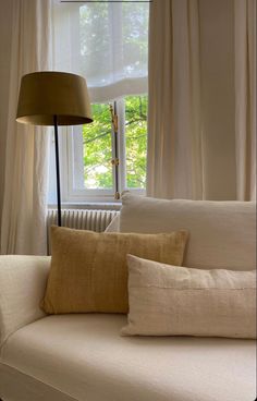 a couch with pillows and a lamp in front of it on the screen, next to a window