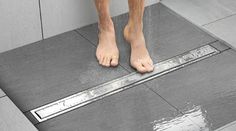 a person standing on a shower floor with their feet in the water