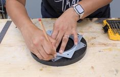 a woman is working on something with a circular object in front of her and holding a pencil