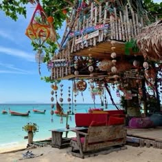 a hut with lots of items hanging from it's roof next to the ocean