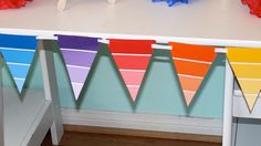 colorful paper buntings are hanging from the ceiling in front of a white desk