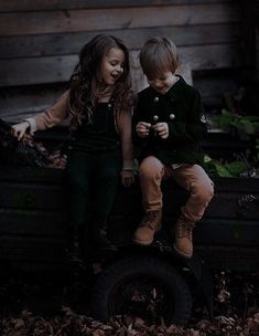 two young children sitting on the back of an old pick up truck with leaves all around them