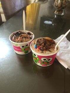 two cups filled with ice cream and toppings on top of a black countertop