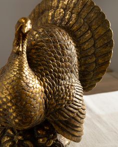 a golden bird statue sitting on top of a wooden table next to a white wall