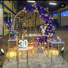 a room filled with balloons and tables covered in purple, gold and white decorations on top of carpeted flooring